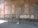 ... Daneben findet sich noch ein weiteres Opfer. Dazwischen sieht man einen der heutigen Bewohner Pompejis. Im Hintergrund sieht man eine der erhaltenen Wandmalereien. ...