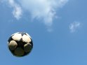 Vor blauem Himmel durch die Luft fliegender Fußball