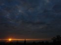 Dunkler Himmel mit einer Wolkenlcke aus der die Sonne kurz vor Sonnenuntergang hervorscheint 
 
Dieses Kartenmotiv ist seit dem 03. August 2006 in der Kategorie Wolken.