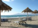 Blick über Strandliegen und Sonnenschirme auf das Mittelmeer und einen strahlend blauen Himmel