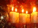Gläserne Kugel zusammen mit mehreren durch ein weihnachtliches Tuch von der Kamera getrennten Kerzen.