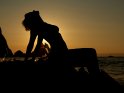 Silhouette einer Frau auf Felsen vor dem Meer bei Sonnenuntergang