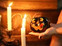 Foto von einer lchelnden Krbisfigur, die von zwei Hnden im Kerzenlicht gehalten wird.