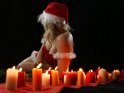 Sexy Frau im Weihnachtskostm hinter einer Reihe brennender Kerzen
