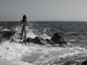 Aktfoto einer Frau auf Felsen am Meer