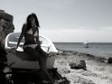 Frau in einem weien Bikini sitzt auf einem weien Boot am Strand.
