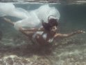 Tauchende Frau im weißen Bikini mit einem weißen Tuch im Meer