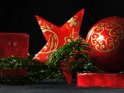 Weihnachtsbild mit roten Weihnachtsobjekten, die mit goldenen Symbolen verziert sind.