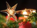 Motiv dieses Weihnachtsbildes ist eine glserne Sternschnuppe mit Tannenzweigen und roten Kerzen im Hintergrund.