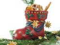 Bunt bemalter Nikolausstiefel steht auf einem Tannenzwei. Der Stiefel ist mit Tannenzweigen, Zimtstangen und Sternen gefüllt.