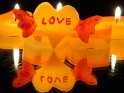 Gelbes Kerze in Form von einem Herz mit roten Flügeln und dem Schriftzug Love