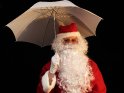 Lustiges Weihnachtsfoto mit einem Weihnachtsmann der einen Regenschirm hält