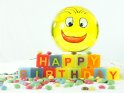 Lustige Geburtstagskarte mit einer mit einem Smilie bemalten Glaskugel und dem aus Buchstaben zusammengesetzem Schriftzug Happy Birthday