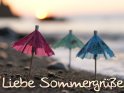 Liebe Sommergrüße 
Diese Karte zeigt drei Cocktail-Schirmchen, die bei Sonnenuntergang an einem Strand stehen.