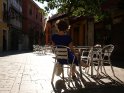 Frau sitzt im blauen Kleid in einem Straßencafé