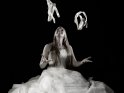 Junge Frau im weißen Kleid jongliert mit Ballettschuhen