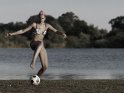 Fußballspielende Frau im Bikini an einem See