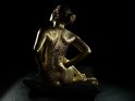 Bodypaintingfoto von einer vergoldeten Frau, die mit dem Rcken zur Kamera auf einem schwarzen Kissen sitzt. 
 
Dieses Motiv findet sich seit dem 30. September 2014 in der Kategorie Bodypainting.