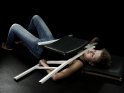 Eine Frau liegt unter einem zerlegten oder nicht zusammengebautem Stuhl.
