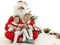 Zwillinge sitzen auf dem Schoß des Weihnachtsmannes und zeigen dabei gerinfügige Unterschiede in ihrer Begeisterung für Weihnachten.