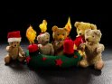 Weihnachtlich gekleidete antike Teddybren mit einem Adventkranz aus Filz an dem zum 3. Advent drei Kerzen brennen.