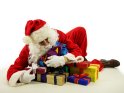 Der Weihnachtsmann stürzt sich auf einen Haufen Geschenke und umschlingt diese mit seinen Armen, als wolle er sie keinesfalls abgeben.