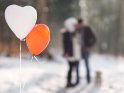 Herzballons mit einem küssenden Paar im Hintergrund.