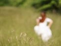 Absichtlich unscharfes Foto von einer Frau im Brautkleid, die ber eine Wiese rennt.