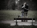 Paar steht küssend im Regen auf einer Bank