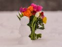 Kleiner Schneemann mit einem Blumenstrauß im Hintergrund