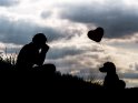 Silhouette einer Frau, die einen Hund mit Herz-Luftballon fotografiert.