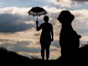 Silhouette einer Frau mit einem Hund. Der Hund steht dabei im Vordergrund, so dass er deutlich größer wirkt.