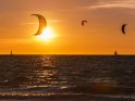 Sonnenuntergang über der Ostsee mit Schirmen von Kitesurfern und zwei Segelbooten