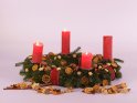 Drei Kerzen brennt zum 3. Advent auf einem Adventskranz mit Orangenscheiben und Zimtstangen vor weißem Hintergrund.