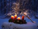 Adventskranz im Schnee mit drei brennenden Kerzen zum 3. Advent.
